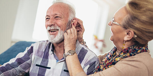 lady checking hearing aid device on a man's ear