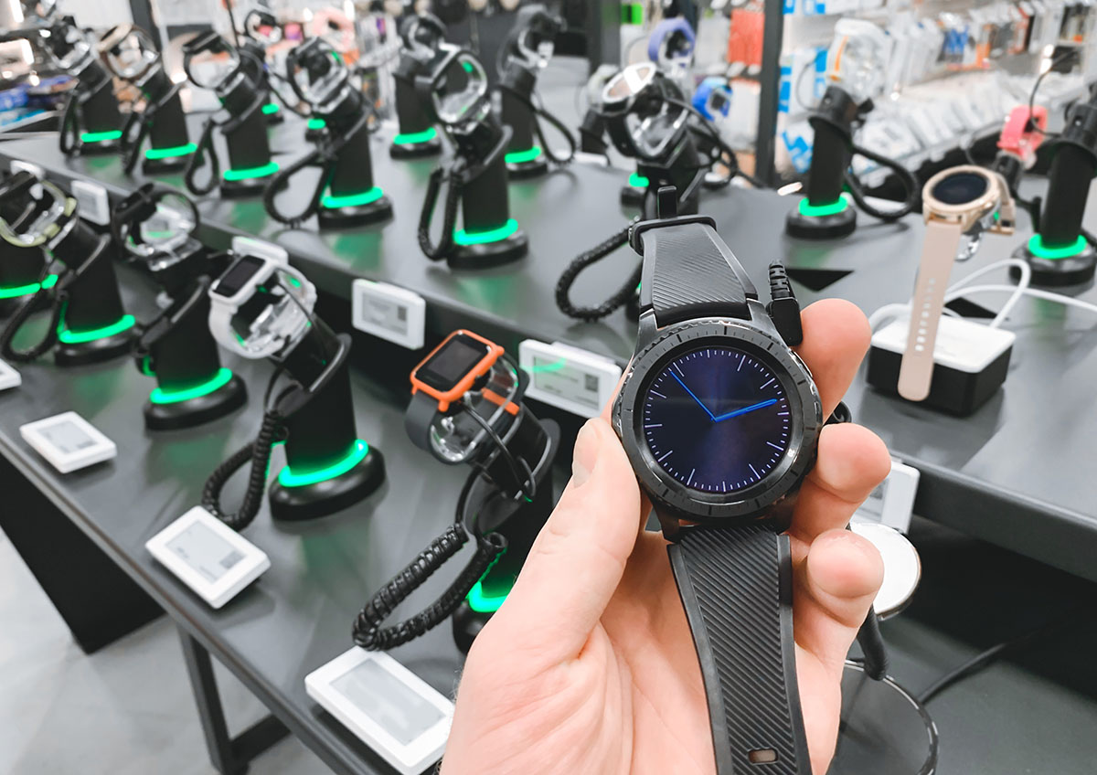 Man in the electronics store holds a smart watch in his hands