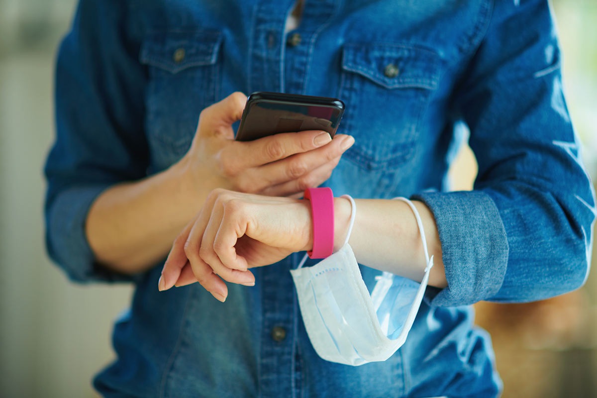 a smartphone and fitness tracker checking stats in the house