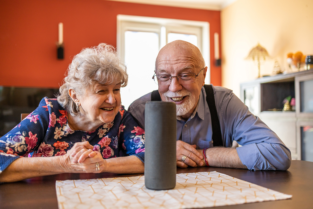 Happy elderly people spending time together at home, using gadgets