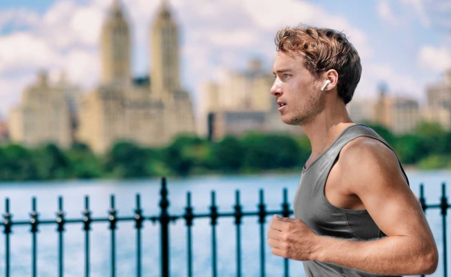 Male jogging with smart earbuds