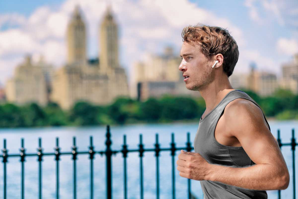 Male jogging with smart earbuds