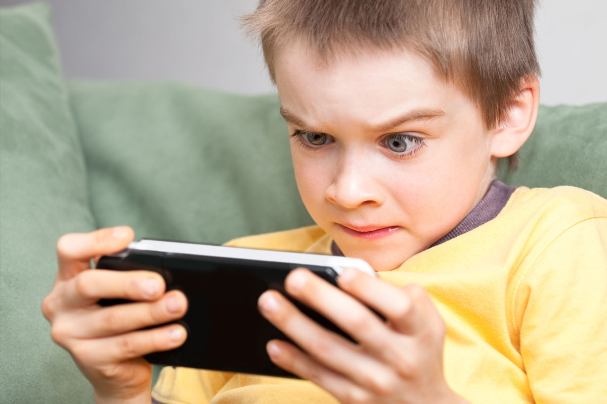 Boy playing handheld gaming console
