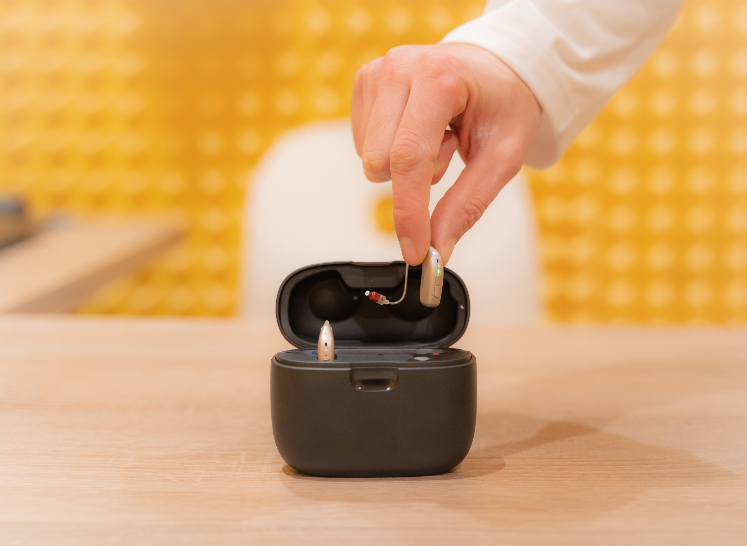 Hand of an audiologist doctor placing a hearing aid in its case.